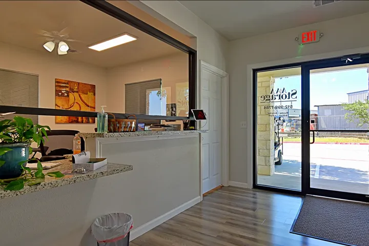 A storage facility office interior with a granite service counter and a glass entrance door with signage