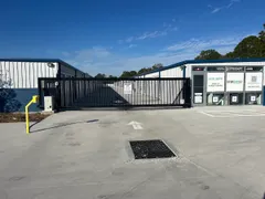 Black metal sliding gate and keypad next to a storage facility office with StorSafe signage