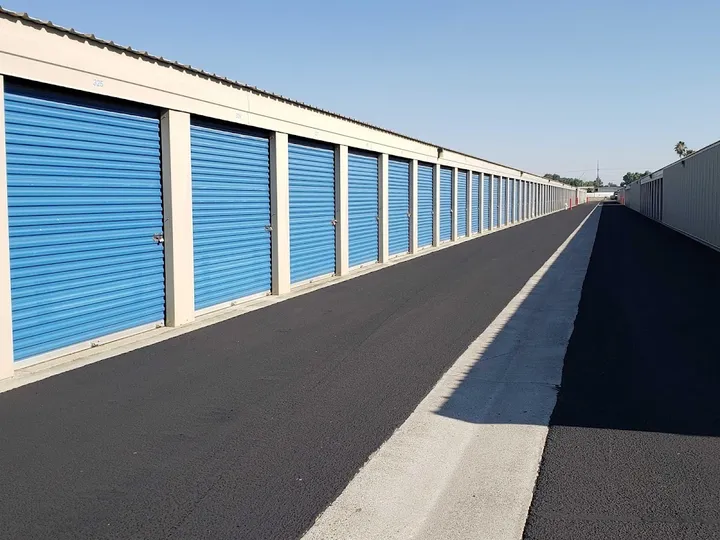 Row of drive-up storage units with blue roll-up doors