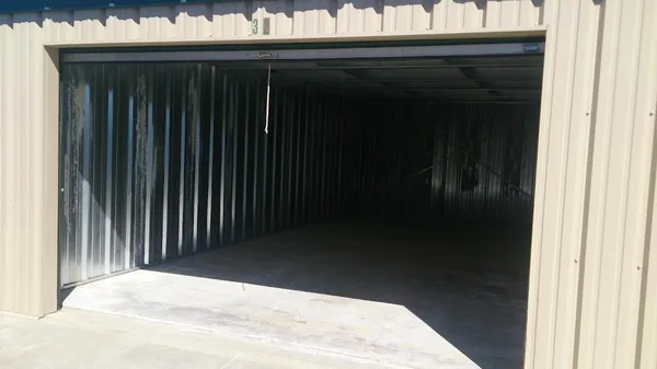 Interior view of an empty drive-up storage unit with metal walls and a concrete floor