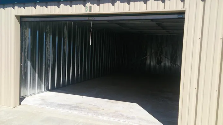 Interior view of an empty drive-up storage unit with metal walls and a concrete floor