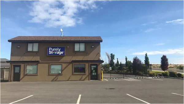 Exterior view of a Purely Storage office building with a paved parking lot and gated entrance