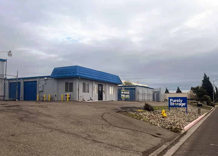 Exterior of a self-storage facility featuring a gray office building with a blue Purely Storage sign