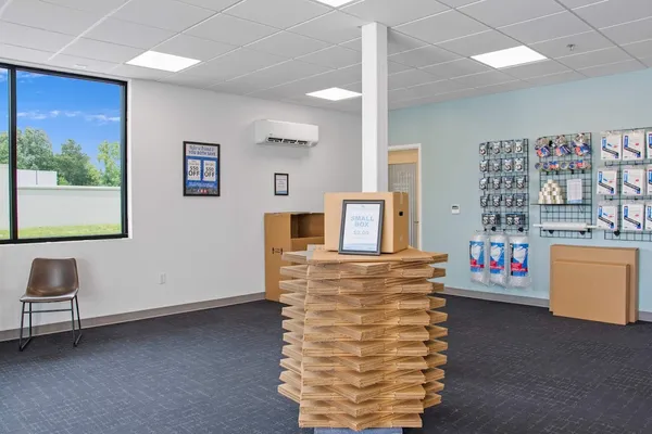 A bright storage rental office featuring a stack of cardboard boxes and moving supplies for sale