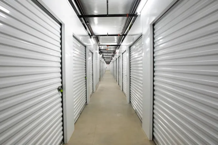 Indoor climate-controlled storage in Augusta, GA, with white corrugated metal unit doors and overhead sprinkler pipes