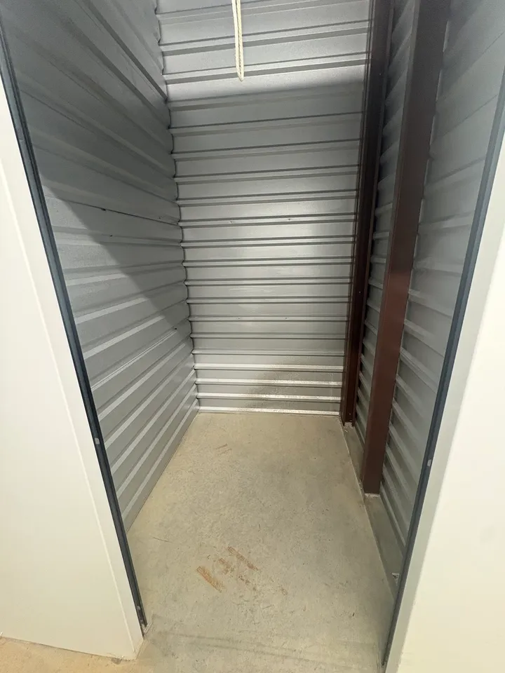 An empty small climate-controlled storage unit in Augusta on Cooper Dr, with corrugated metal walls and a concrete floor