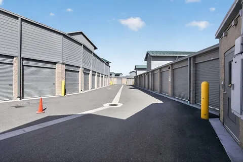 Outdoor drive-up storage units in Park City, UT, at 6344 N Promontory Ranch Rd, with gray roll-up doors along a wide asphalt driveway under a blue sky