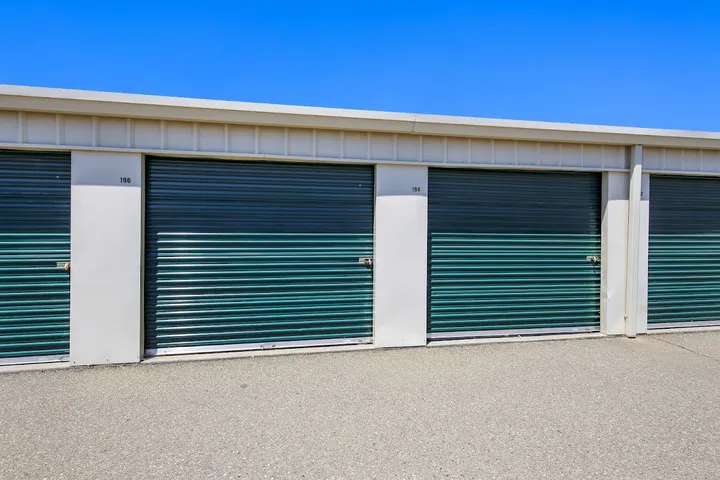 Close-up view of several green roll-up storage unit doors.