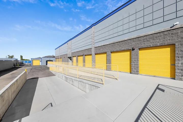 Exterior view of storage units with yellow doors and access ramp.
