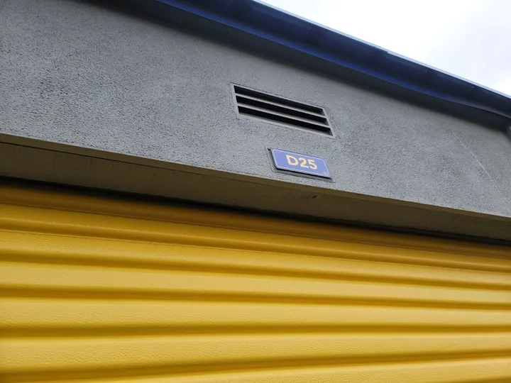 Yellow roll-up unit door with unit number D25 visible.