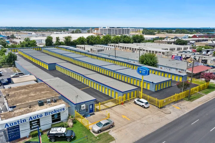 Aerial view of self-storage facility with yellow unit doors and a pole sign.