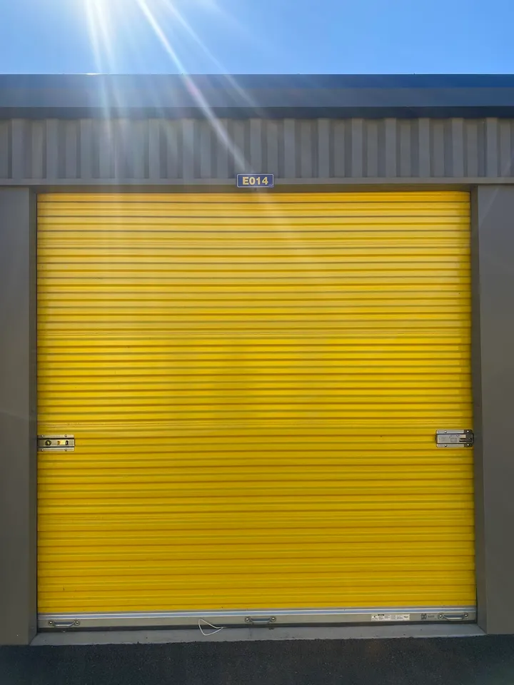 Close-up of a bright yellow roll-up storage unit door labeled 'E014'.