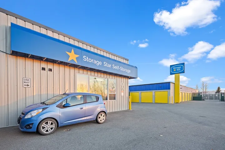 Exterior of storage facility office and driveway with a car parked.