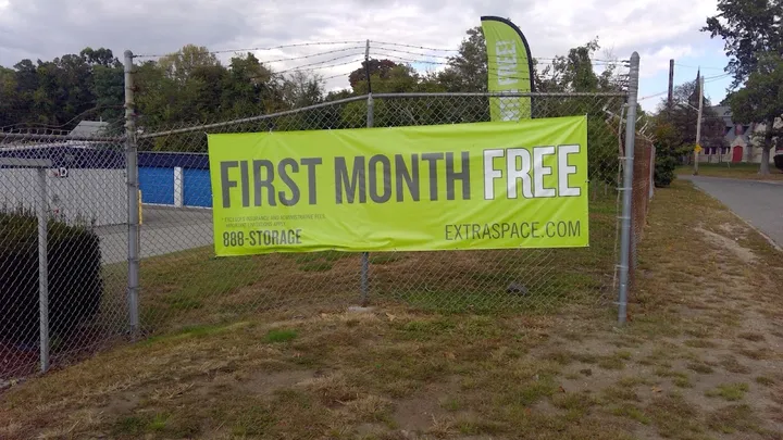 Promotional banner for 'First Month Free' on a chain link fence.