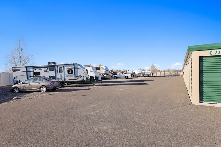 Outdoor RV and car parking area next to storage units