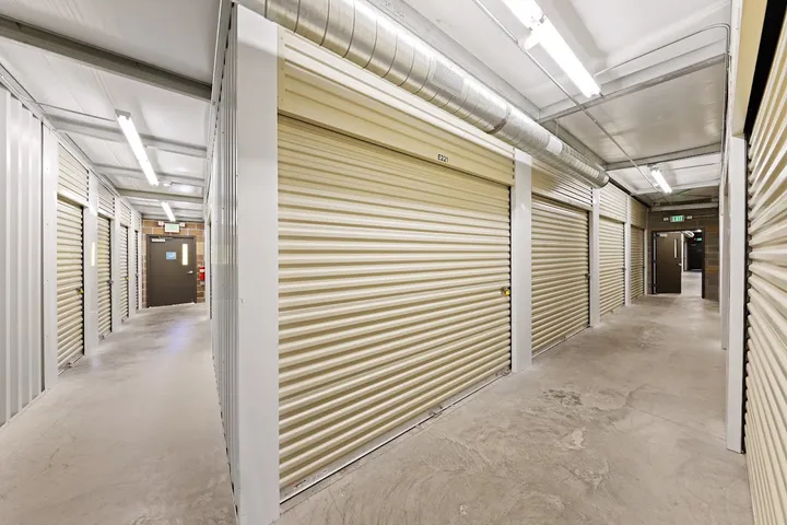 Indoor climate-controlled storage unit hallway with tan rollup doors.