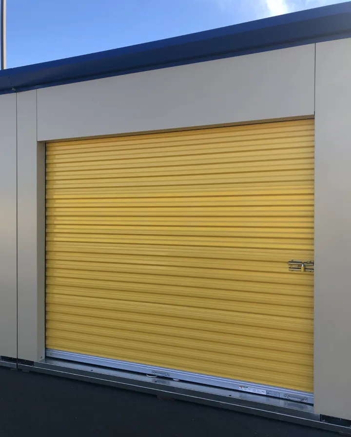 Yellow drive-up storage unit door with a padlock.