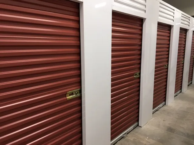 Row of red storage unit doors in an indoor hallway.