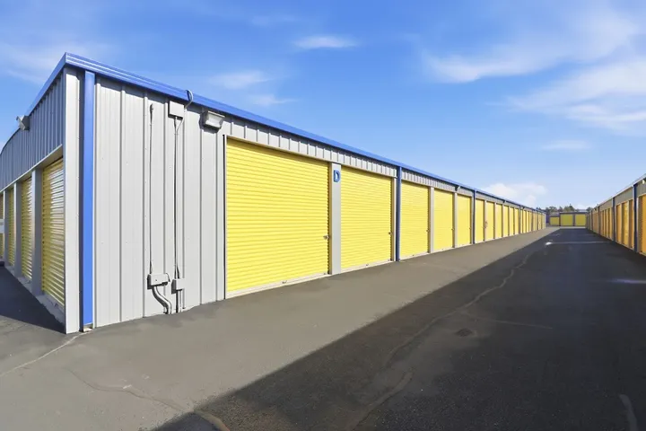 Long row of drive-up storage units with yellow doors.