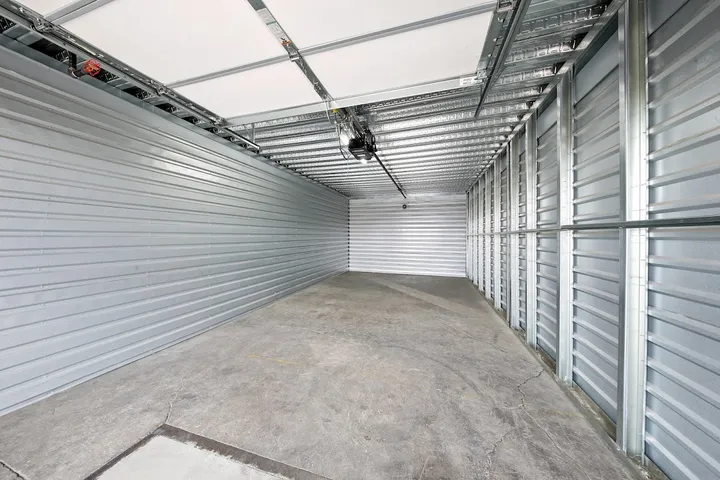 Empty indoor storage unit with corrugated metal walls and concrete floor
