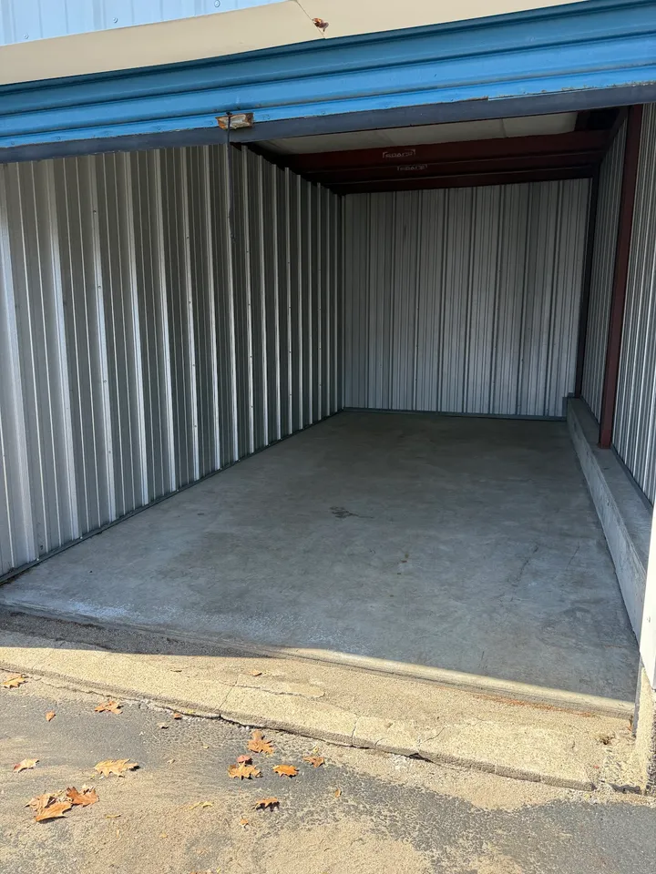Interior of an empty drive-up storage unit with a blue roll-up door