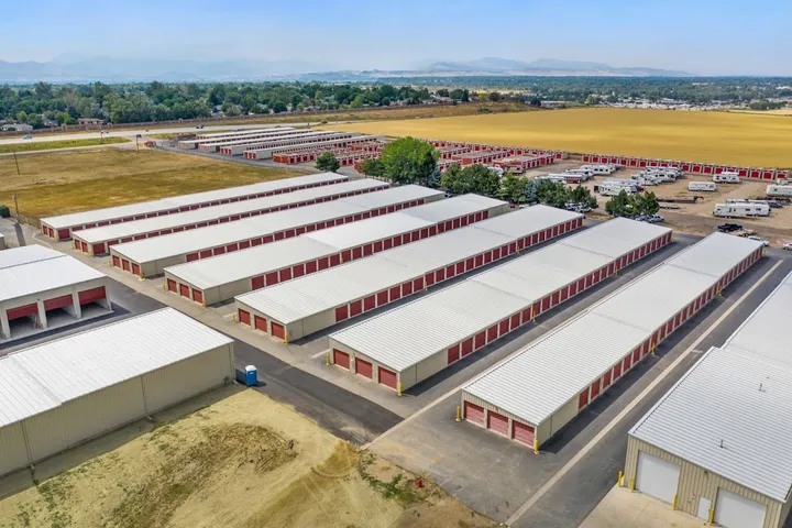 A bird's-eye view of drive-up storage units and surrounding farmland.