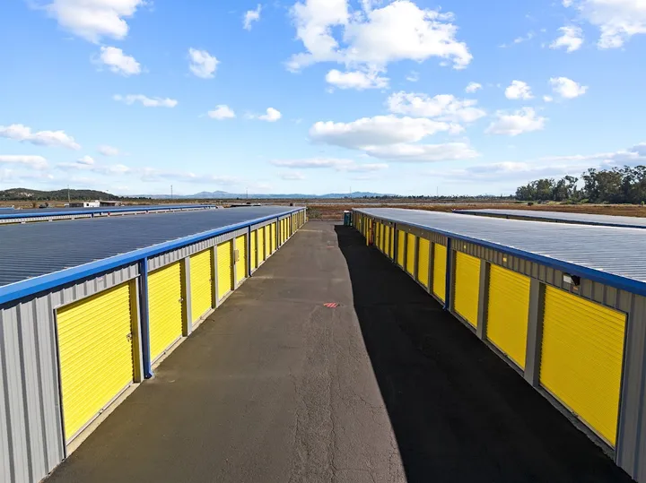 Outdoor drive-up storage units with yellow doors on a clear day