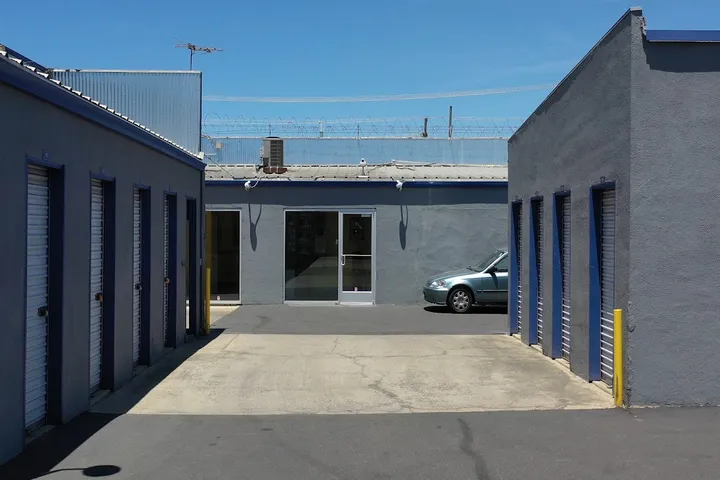 Outdoor storage units and entrance to office area with a car parked.