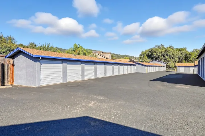 Row of drive-up storage units with sky blue doors and grey exteriors