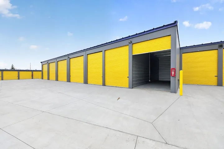 Exterior of storage units with bright yellow doors, one unit door open.