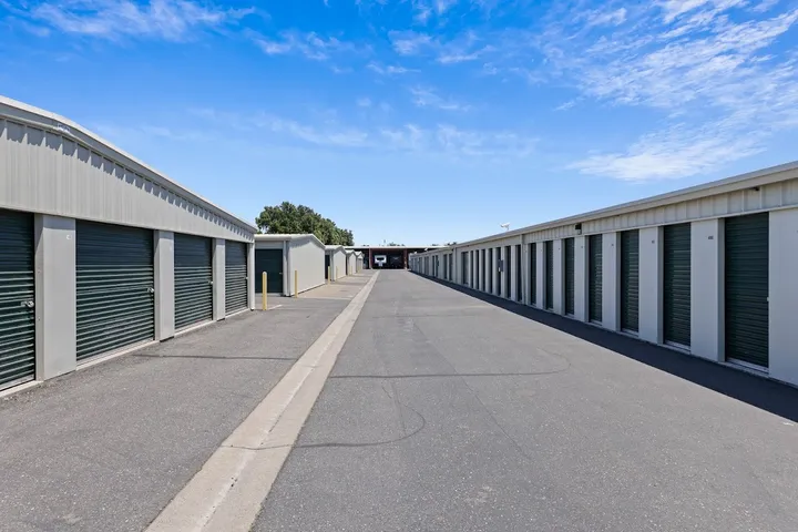 Long rows of outdoor storage units with green roll-up doors.