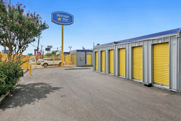 Storage facility with yellow unit doors and a blue-and-yellow pole sign.