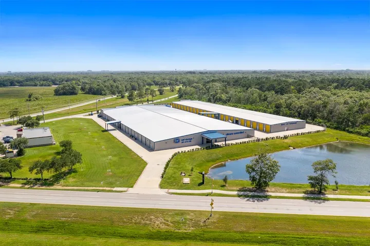 Aerial view of storage facility buildings and surrounding landscape with pond