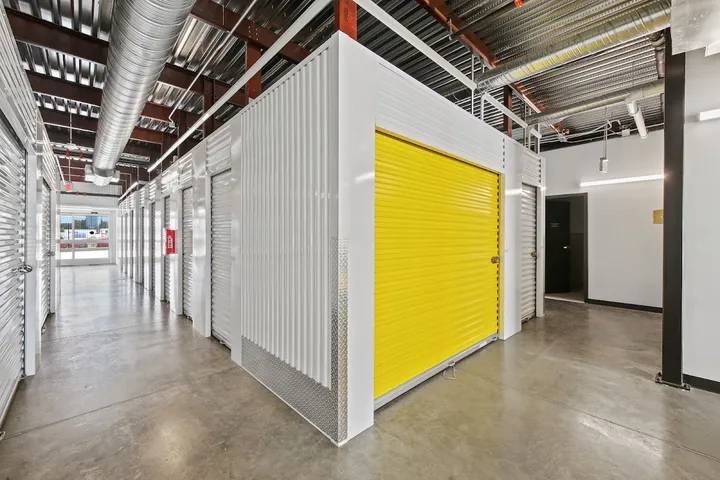 Indoor hallway with various storage unit doors, one yellow.