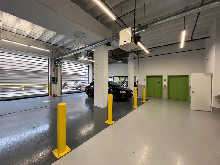 Indoor drive-up loading bay area with green elevator doors and car.