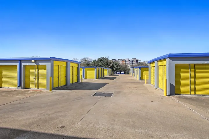 Storage unit drive-up with rows of yellow storage doors.