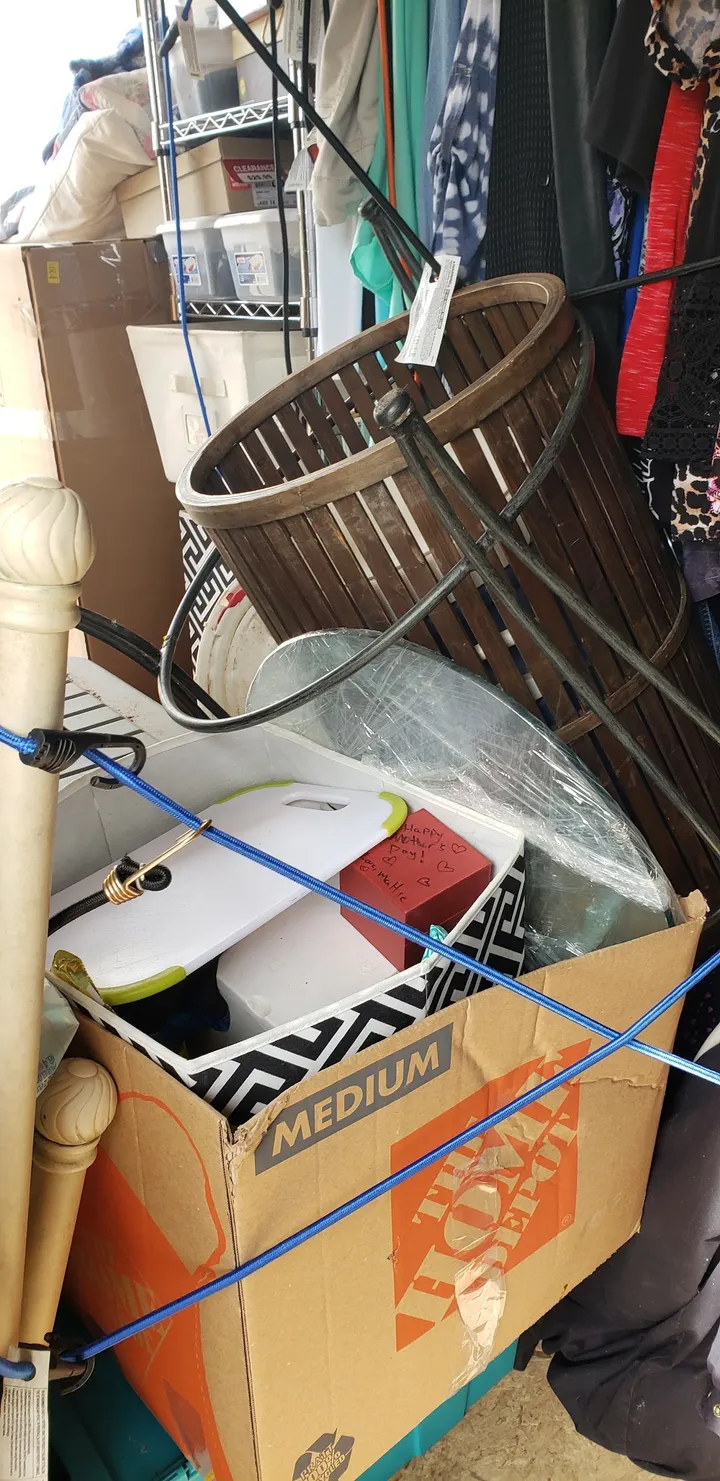 Cluttered interior of a storage unit with boxes and household items.