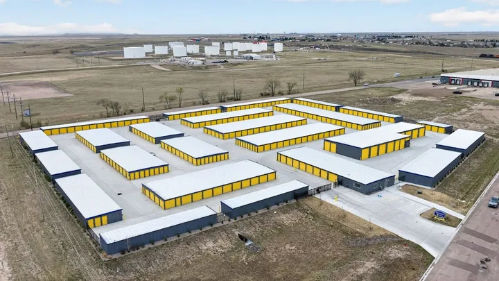 Wide aerial view of a self-storage facility with many buildings and yellow doors.