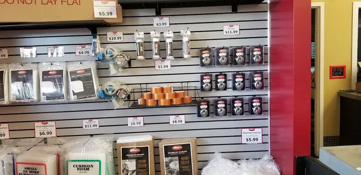 Retail display of packing supplies including boxes, tape, and locks.