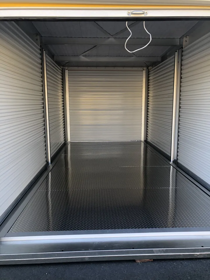 Empty storage unit interior with corrugated walls and diamond plate floor.