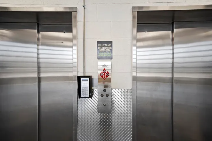 Two elevators with a keypad and control panel.