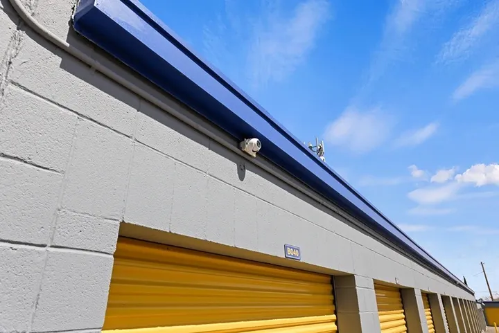Row of yellow roll-up unit doors with security camera.