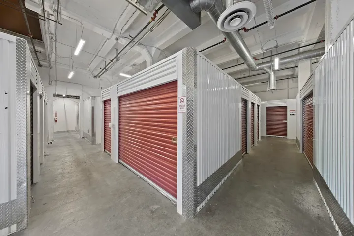 Main aisle of indoor storage units with red roll-up doors.