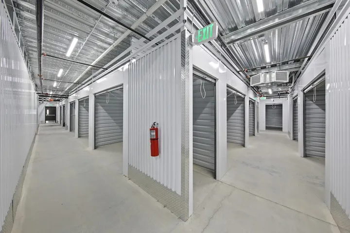 Indoor hallway with many storage units and an exit sign.