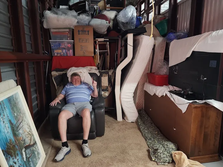 Customer sitting in a recliner within a packed storage unit.