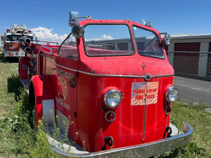 Front view of an old red fire truck used as a decorative display.