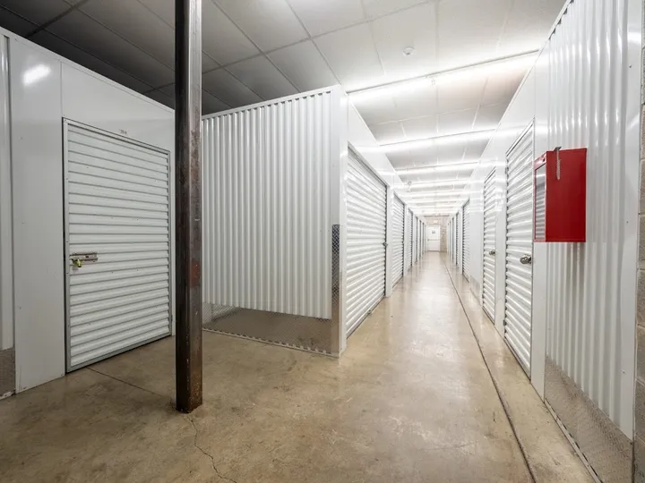 A climate-controlled storage hallways in Chicago, IL, with white corrugated metal storage unit doors and a red fire extinguisher cabinet