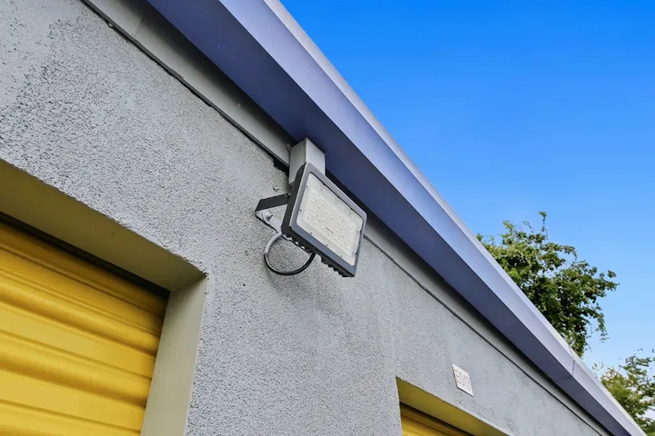Close-up of exterior wall with a security light and yellow unit door.