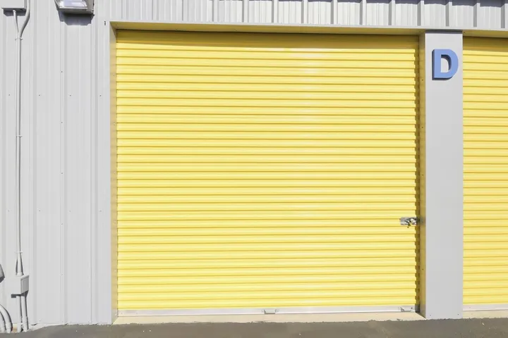 Yellow roll-up storage unit door with unit letter 'D'.