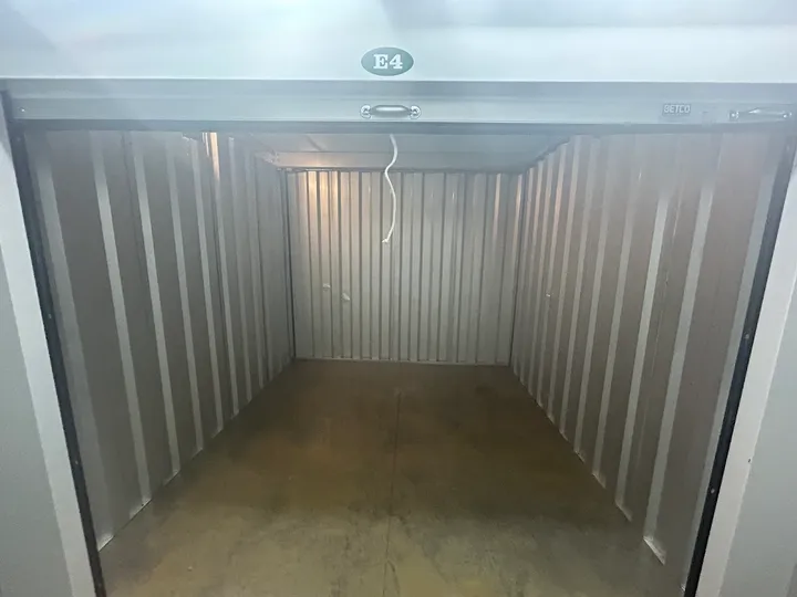 Interior view of an empty self-storage unit with a roll-up door.